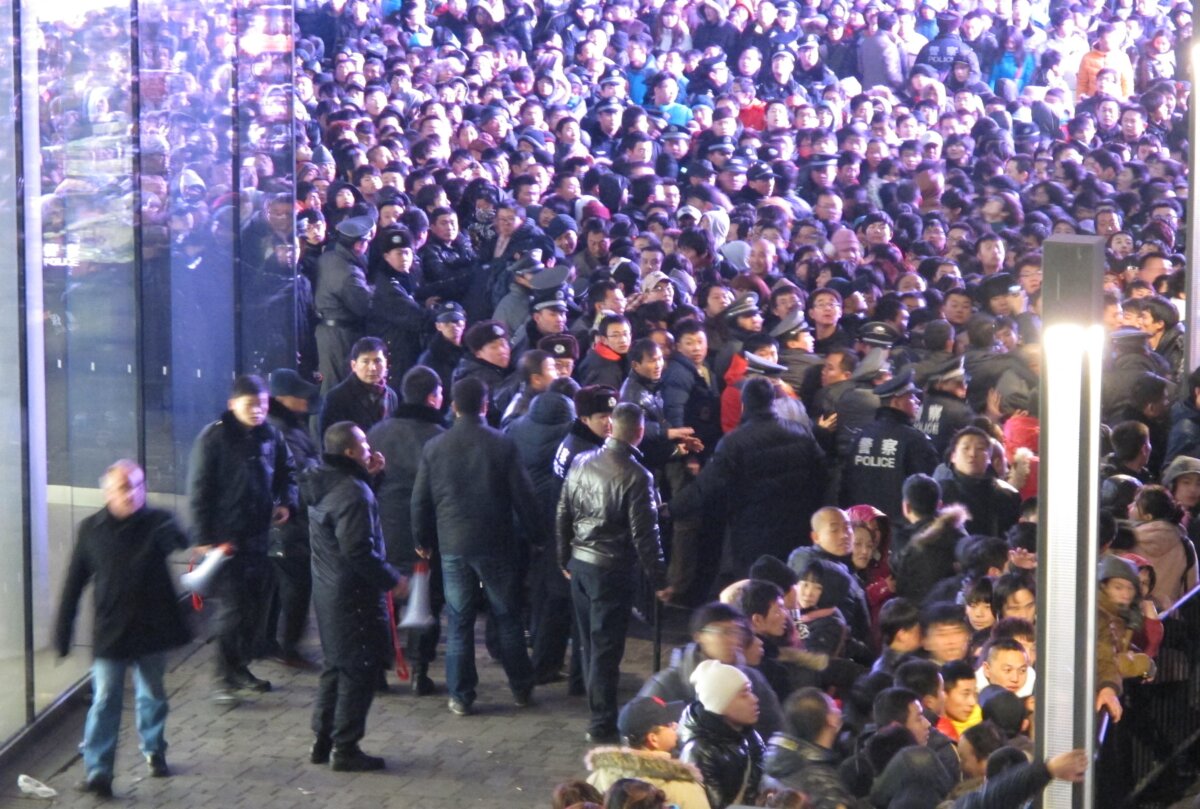 Cảnh sát cố gắng phong tỏa khu vực khi hàng ngàn khách hàng xếp hàng bên ngoài một cửa hàng Apple ở khu mua sắm cao cấp Tam Lý Truân (Sanlitun) của Bắc Kinh, ở Bắc Kinh, vào sáng sớm ngày 13/01/2012. (Ảnh: AFP qua Getty Images)